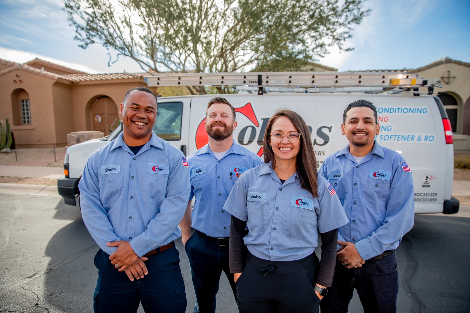 Four smiling Collins Comfort techs standing in front of their work van